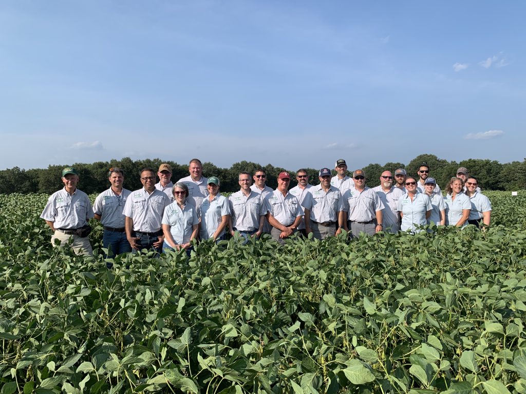 Photo of a group of people in matching shirts standing in a soybean field